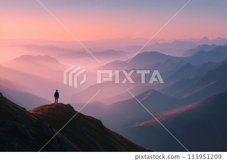 Lone Hiker on Mountain Peak at Sunrise 133951209