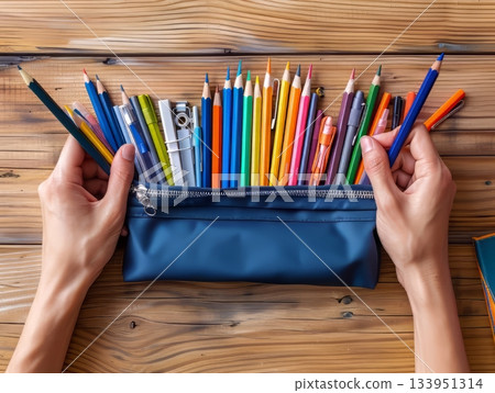 Pencil case with hands on wooden desk Pencil case with hands on wooden desk 133951314