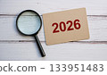 Magnifying Glass Focusing on Red 2026 Text on Cardboard Paper for Future Planning or Forecast Concept 133951483