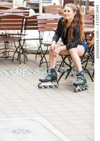 Young woman sitting wearing roller skates 133951645