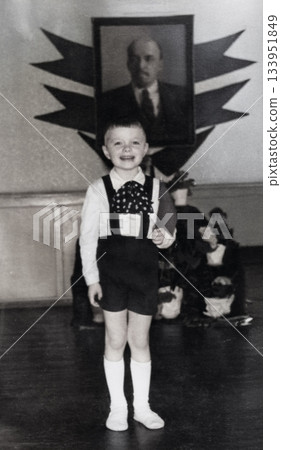 A vintage portrait of a young Soviet boy reading a poem and holding a flag in front of a portrait of Lenin. Photo from 1966 A vintage portrait of a young Soviet boy reading a poem and holding a flag in front of a portrait of Lenin. Photo from 1966 133951849