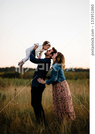 Family Joy Captured During Sunset in an Open Field With a Playful Child 133951860