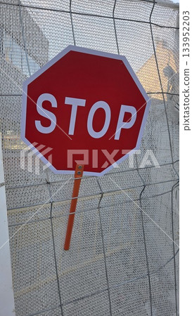 Red stop sign on construction site fence for traffic safety and awareness Red stop sign on construction site fence for traffic safety and awareness 133952203