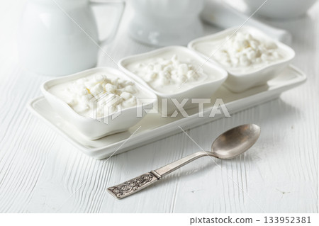 Cottage cheese with cream on a white table. 133952381