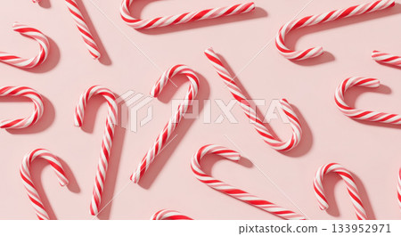 Festive candy canes arranged playfully on a soft pink background, creating a cheerful and vibrant Christmas concept for holiday celebrations 133952971