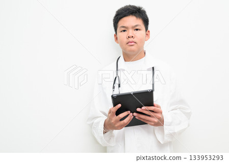 Young Asian Boy Dressed as Doctor with Stethoscope Using Digital Tablet Computer Young Asian Boy Dressed as Doctor with Stethoscope Using Digital Tablet Computer 133953293