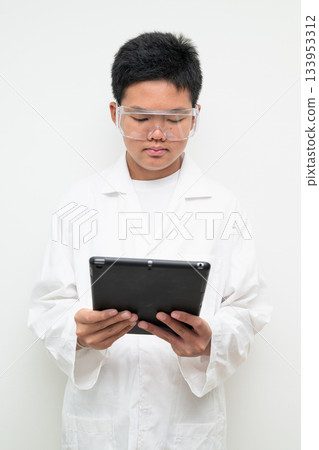 Young Asian Boy Dressed as Scientist with Lab Coat Using Digital Tablet Computer Young Asian Boy Dressed as Scientist with Lab Coat Using Digital Tablet Computer 133953312