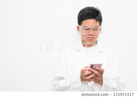 Young Asian Boy Dressed as Scientist with Lab Coat Using Mobile Phone Texting 133953317
