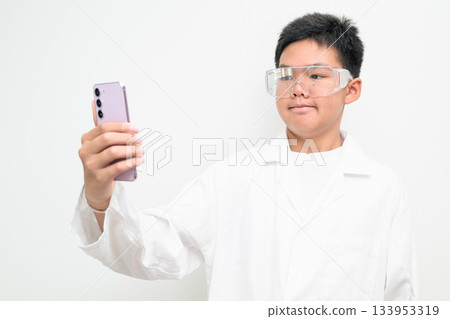 Young Asian Boy Dressed as Scientist with Lab Coat Using Mobile Phone Young Asian Boy Dressed as Scientist with Lab Coat Using Mobile Phone 133953319