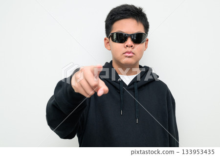 Asian Teenage Boy in Hoodie Wearing Sunglasses Pointing at Camera 133953435