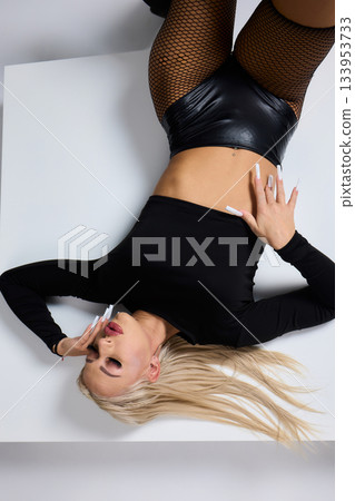 Vivid fashion scene, Dynamic photograph capturing bold fashion and fierce attitude, Fashion model leans against white cube showcasing daring attire and intense expression Vivid fashion scene, Dynamic photograph capturing bold fashion and fierce attitude, Fashion model leans against white cube showcasing daring attire and intense expression 133953733