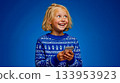 A little girl in a blue sweater holding a cell phone 133953923