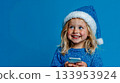 A little girl in a Santa hat holding a cell phone 133953924