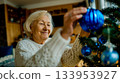 A woman decorating a Christmas tree with blue ornaments 133953927