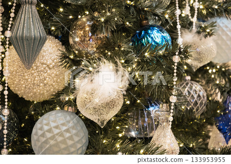 Luxurious blue and silver ornaments with delicate textures and lights decorating Christmas tree for an elegant winter celebration. 133953955