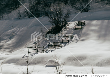 Snow-covered landscape with wooden fences in a remote area during winter Snow-covered landscape with wooden fences in a remote area during winter 133953956