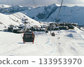 Ski lift transports visitors to a mountain resort during winter in a snowy landscape 133953970