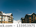 Snowy buildings under clear blue sky in mountain location during winter season 133953975