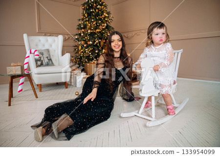 Family celebration with a young girl in a cozy room decorated for the holidays during a joyful festive gathering 133954099