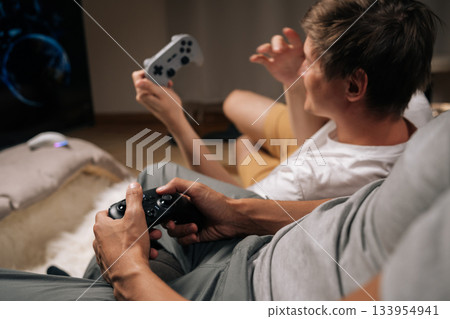 Friends gaming together at home, enjoying console video games during leisure time, having fun and unwinding while sharing entertaining moments and screen time. Friends gaming together at home, enjoying console video games during leisure time, having fun and unwinding while sharing entertaining moments and screen time. 133954941