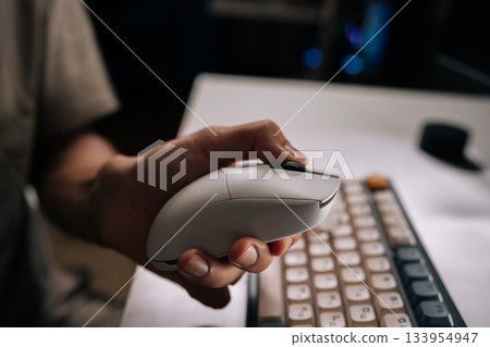 Close-up hands of man cleaning computer mouse and keyboard with disposable wipe, emphasizing hygiene and sanitation for workspace and technology during daily routines at home or office, close-up. 133954947