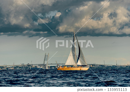 The lonely old wooden sailboat at sunny day, bridge on background, sailing regatta in the Gulf of Finland, sailing yacht competing in a race, splashing water, board the boat 133955113