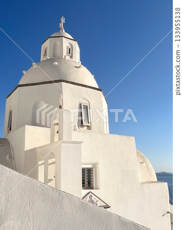 White washed church showcasing traditional cycladic architecture with a prominent dome and cross, set against a vibrant blue sky on a greek island, representing travel and tourism White washed church showcasing traditional cycladic architecture with a prominent dome and cross, set against a vibrant blue sky on a greek island, representing travel and tourism 133955138