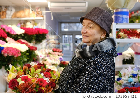 Flower shop, adult elderly woman choosing a bouquet, wearing a hat and coat, autumn-winter 133955421