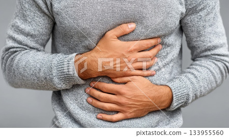 Man holding stomach in discomfort 133955560