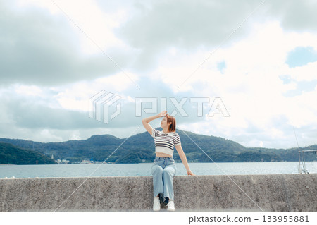 一位二十多歲的女子向大海張開雙臂。這是旅途中感受到的自由與解放的動人瞬間。 133955881