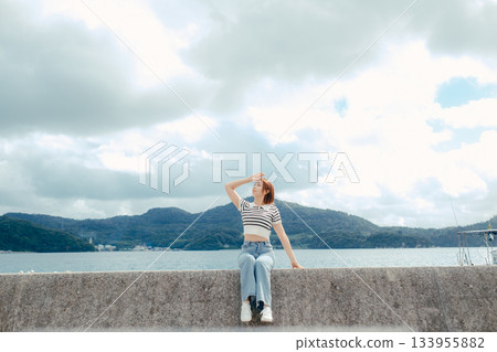 一位二十多歲的女子向大海張開雙臂。這是旅途中感受到的自由與解放的動人瞬間。 133955882