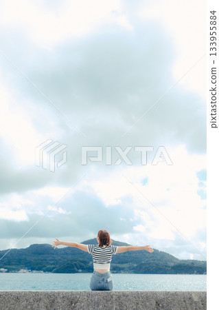 一位二十多歲的女子向大海張開雙臂。這是旅途中感受到的自由與解放的動人瞬間。 133955884