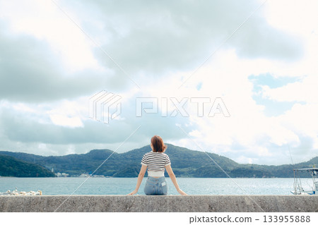 一位二十多歲的女子向大海張開雙臂。這是旅途中感受到的自由與解放的動人瞬間。 133955888