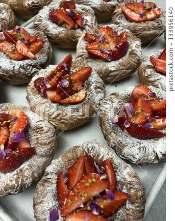 A delightful fruit tart with a buttery, flaky crust filled with creamy custard and topped with an array of fresh, vibrant fruits. Perfectly balanced between sweet and tangy, making it irresistible 133956140