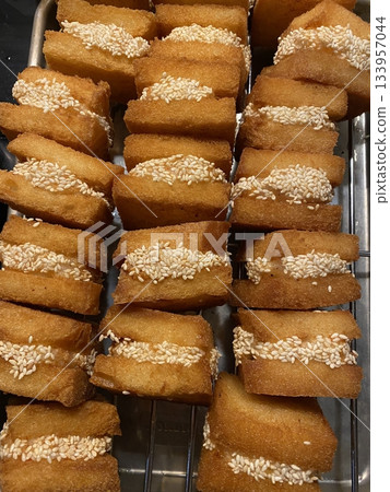 Menbosha shrimp toast with golden crispy bread enclosing tender shrimp filling, highlighting crunchy texture, juicy interior, and rich golden-brown color in close-up appetizing detail 133957044