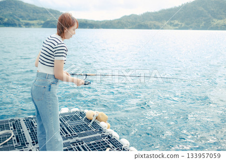 一位女士在海灘享受釣魚的樂趣 一位女士在海灘享受釣魚的樂趣 133957059