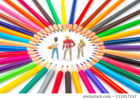 A creative composition featuring three small figures within a circle of assorted colored pencils 133957241