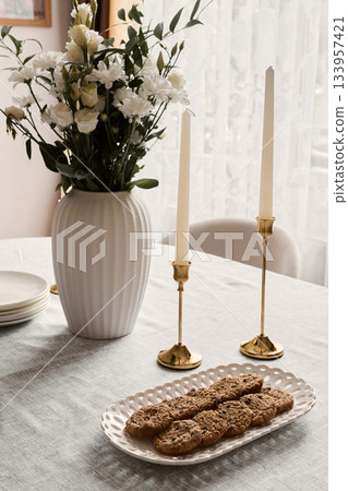 Comfortable table setting with flowers, Inviting cozy dining scene with candles and cookies 133957421