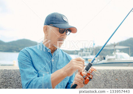 一位老人正在看釣竿 133957443