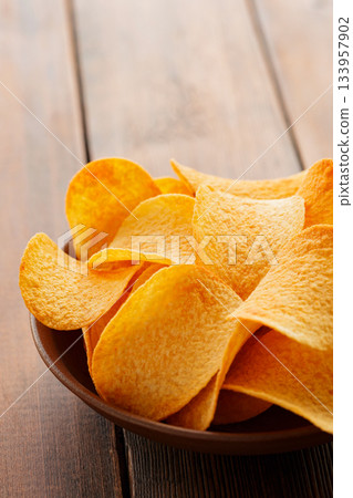 Golden Crispy Potato Chips in Bowl on Wooden Table Close-Up Golden Crispy Potato Chips in Bowl on Wooden Table Close-Up 133957902