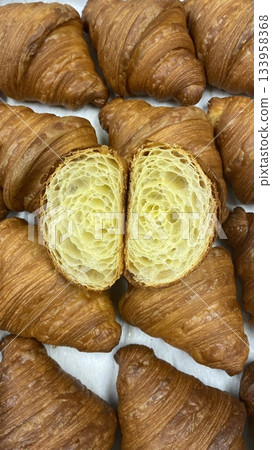 A croissant is a classic French pastry known for its buttery, flaky layers and golden crust. Often enjoyed plain or filled with chocolate, almond, or ham and cheese, it’s a perfect for breakfast 133958368