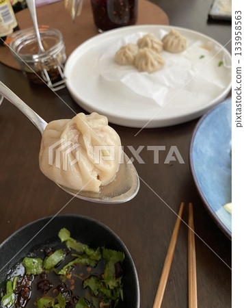 Steamed xiaolongbao dumplings with delicate thin skin, slightly translucent top folds, and savory soup filling inside, highlighting their soft texture and freshly steamed appearance in close-up detail Steamed xiaolongbao dumplings with delicate thin skin, slightly translucent top folds, and savory soup filling inside, highlighting their soft texture and freshly steamed appearance in close-up detail 133958563