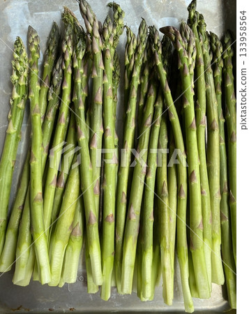 Fresh green asparagus stalks with smooth, firm texture and tightly closed tips, showcasing vibrant color, natural shine, and crisp freshness in close-up detail Fresh green asparagus stalks with smooth, firm texture and tightly closed tips, showcasing vibrant color, natural shine, and crisp freshness in close-up detail 133958564