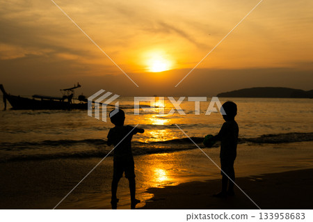 Children playing in the sea at sunset Children playing in the sea at sunset 133958683