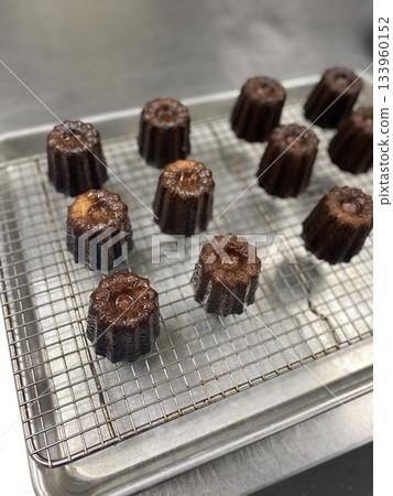 Canelé, a classic French pastry with a caramelized crust and soft, custard-like center, infused with vanilla and rum. Perfect for dessert photography, showcasing the elegant texture and rich flavor. 133960152