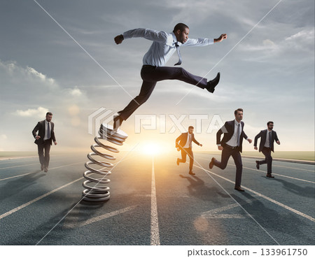 Man jumps off a spring while other men run on track during sunset hours in a competitive setting 133961750