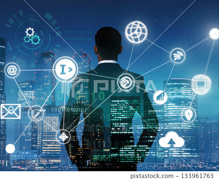 Business professional looks at digital connections over city skyline at night with clouds in background 133961763