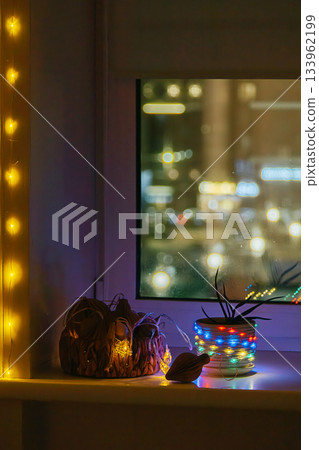 Festive string lights glowing on windowsill at night. Festive string lights glowing on windowsill at night. 133962199
