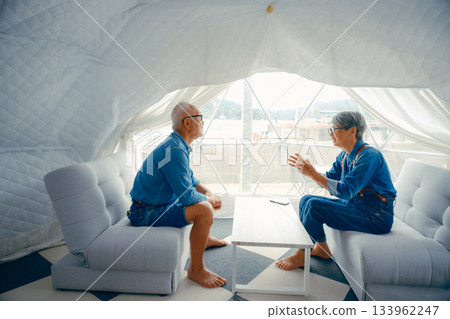 Conversation scene of a senior couple relaxing at a glamping facility 133962247
