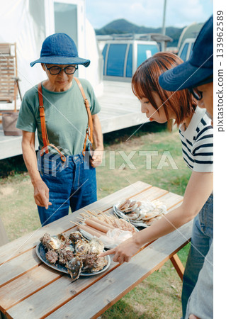 三個家長帶著孩子在湖邊享受燒烤的場景 133962589